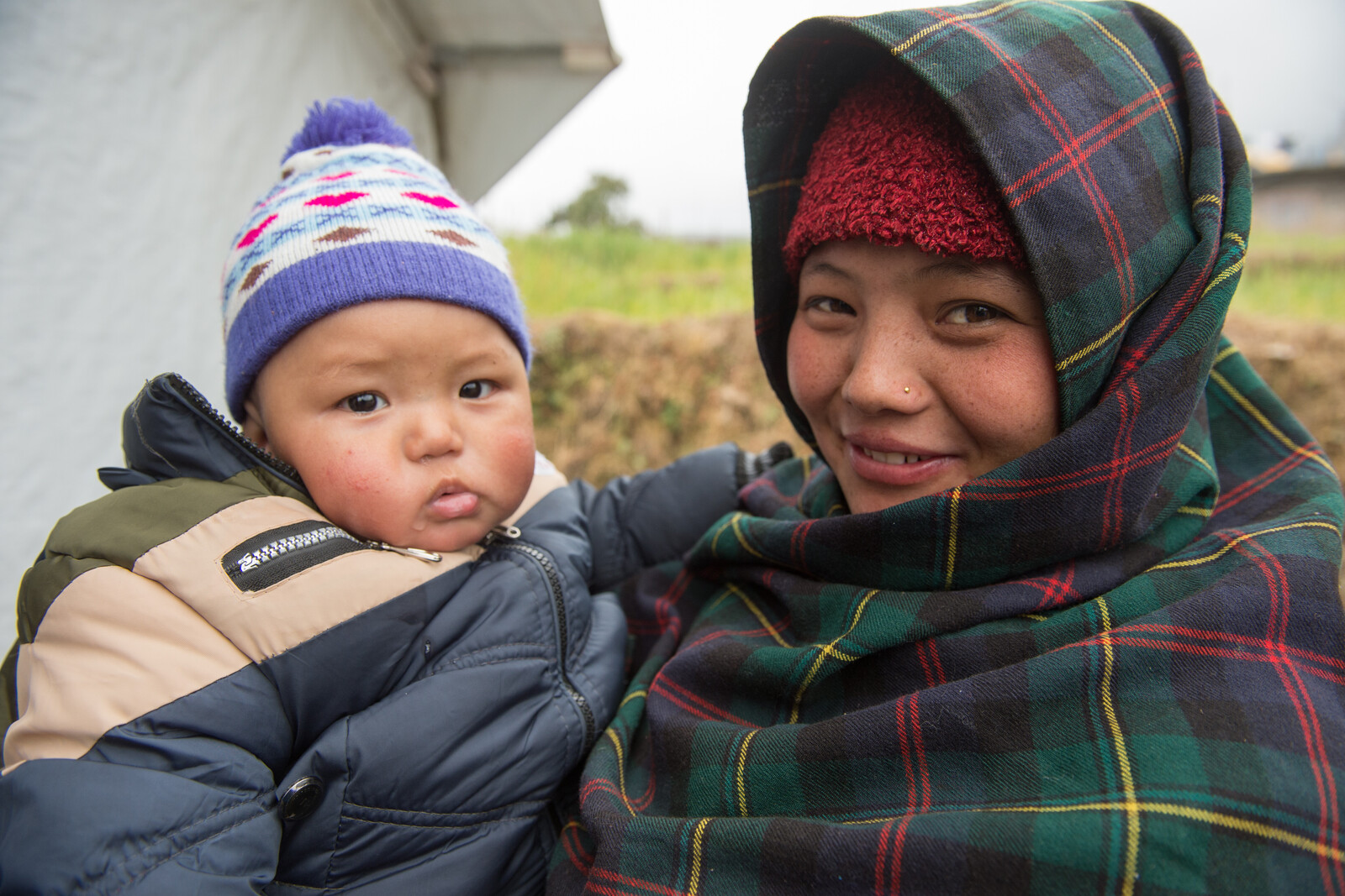 Eine Frau steht mit ihrem Kind vor einem Female Friendly Space nach dem Erdbeben in Nepal.