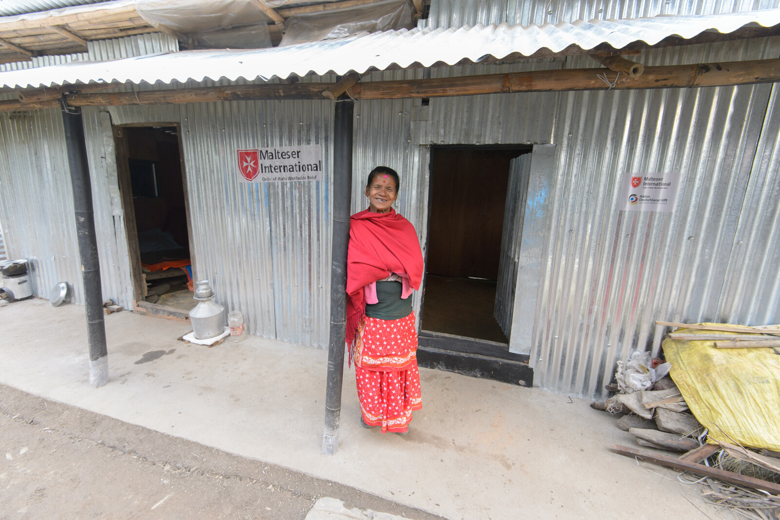 Eine taubstumme Frau steht vor ihrem neu errichteten Zuhause in Nepal nach dem Erdbeben.