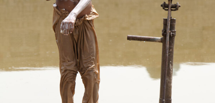 Flut Pakistan: Junge wäscht sich an einer Pumpe