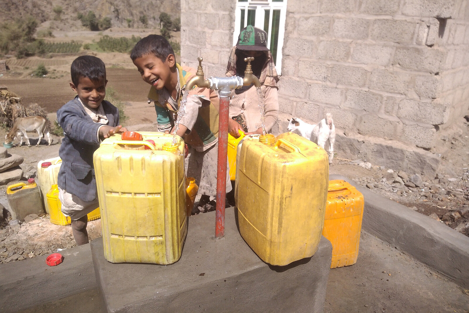 Zwei Jungs im Jemen spielen mit zwei gelben Wasserkanistern.
