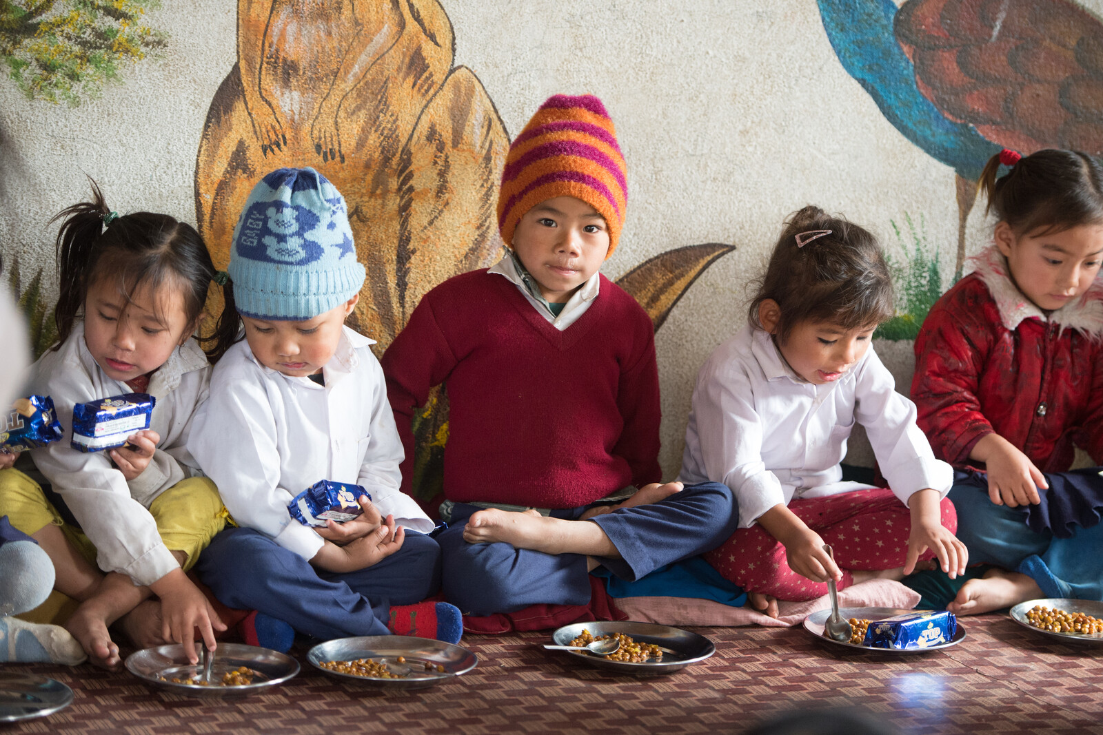 Kinder essen in einer nach dem Erdbeben in Nepal wieder aufgebauten Schule zu Mittag.