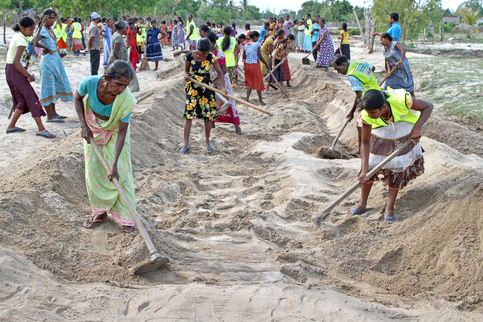 Frauen legen in Sri Lanka einen Sanddamm an. Das Wasser kann zur Bewässerung der Felder in Trockenzeiten verwendet werden.