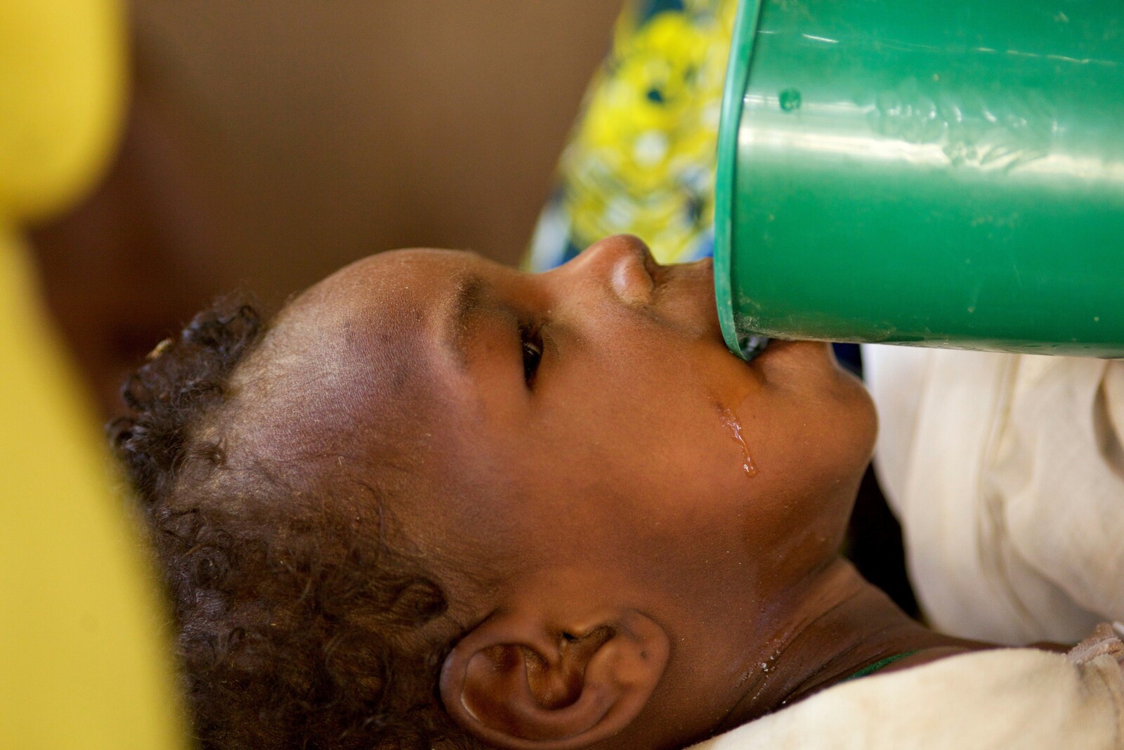 Ein geflüchtetes Kind trinkt Wasser. Das Mädchen ist mit seiner Familie aus Nigeria geflohen.