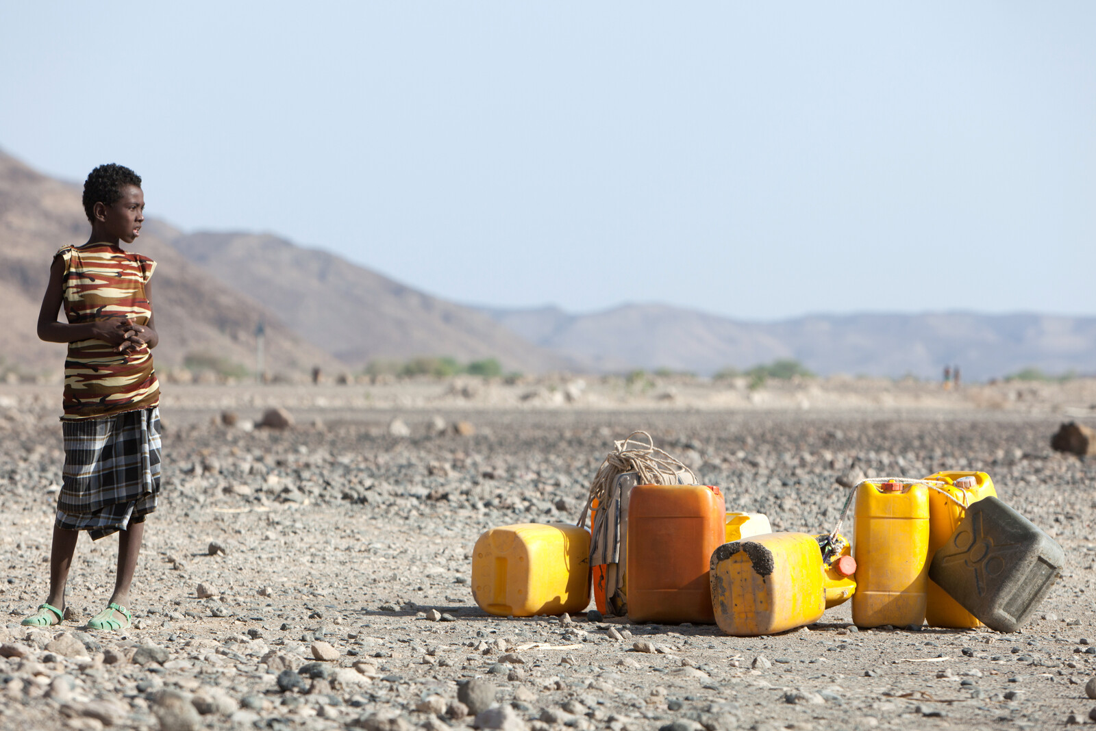 Ein Junge in Äthiopien steht neben Wasserkanistern