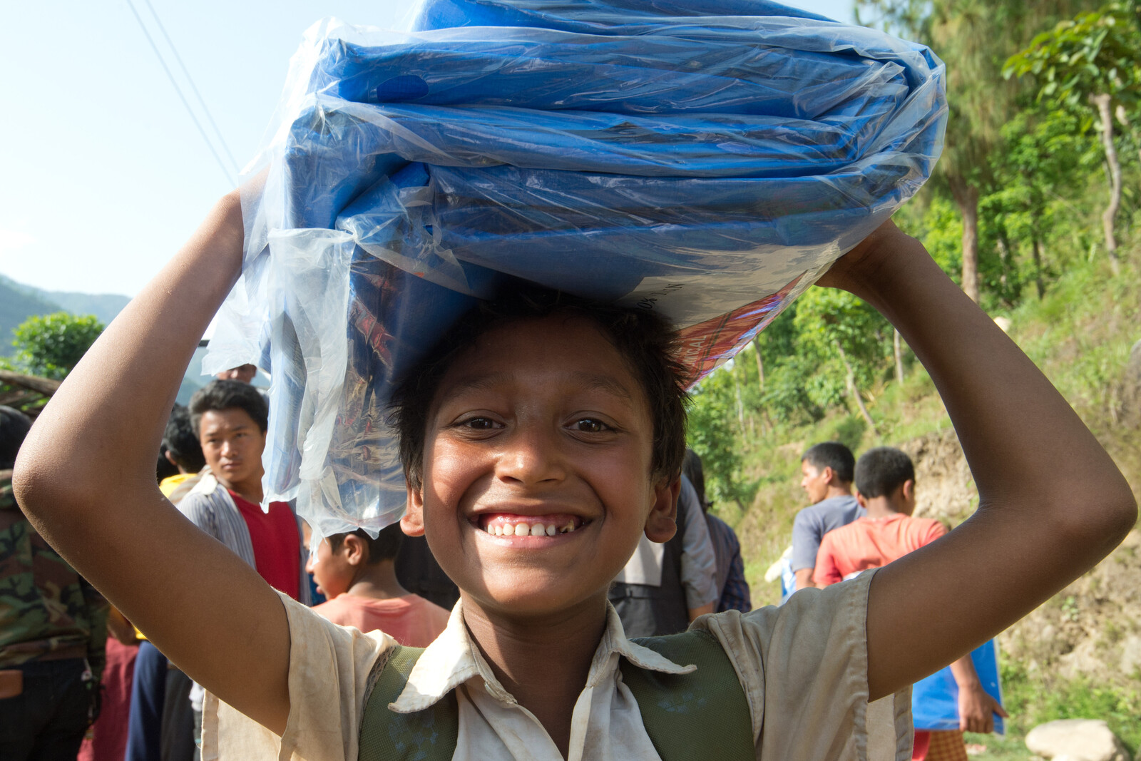 Erdbeben Nepal - Ein Junge erhält Decken und Zeltplanen.