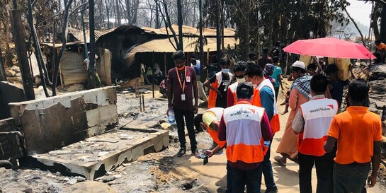 Helfer:innen begutachten Schäden nach Brand in Flüchtlingslager der Rohingya.