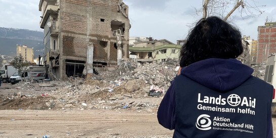 Eine Helferin von LandsAid blickt auf ein vom Erdbeben zerstörtes Haus