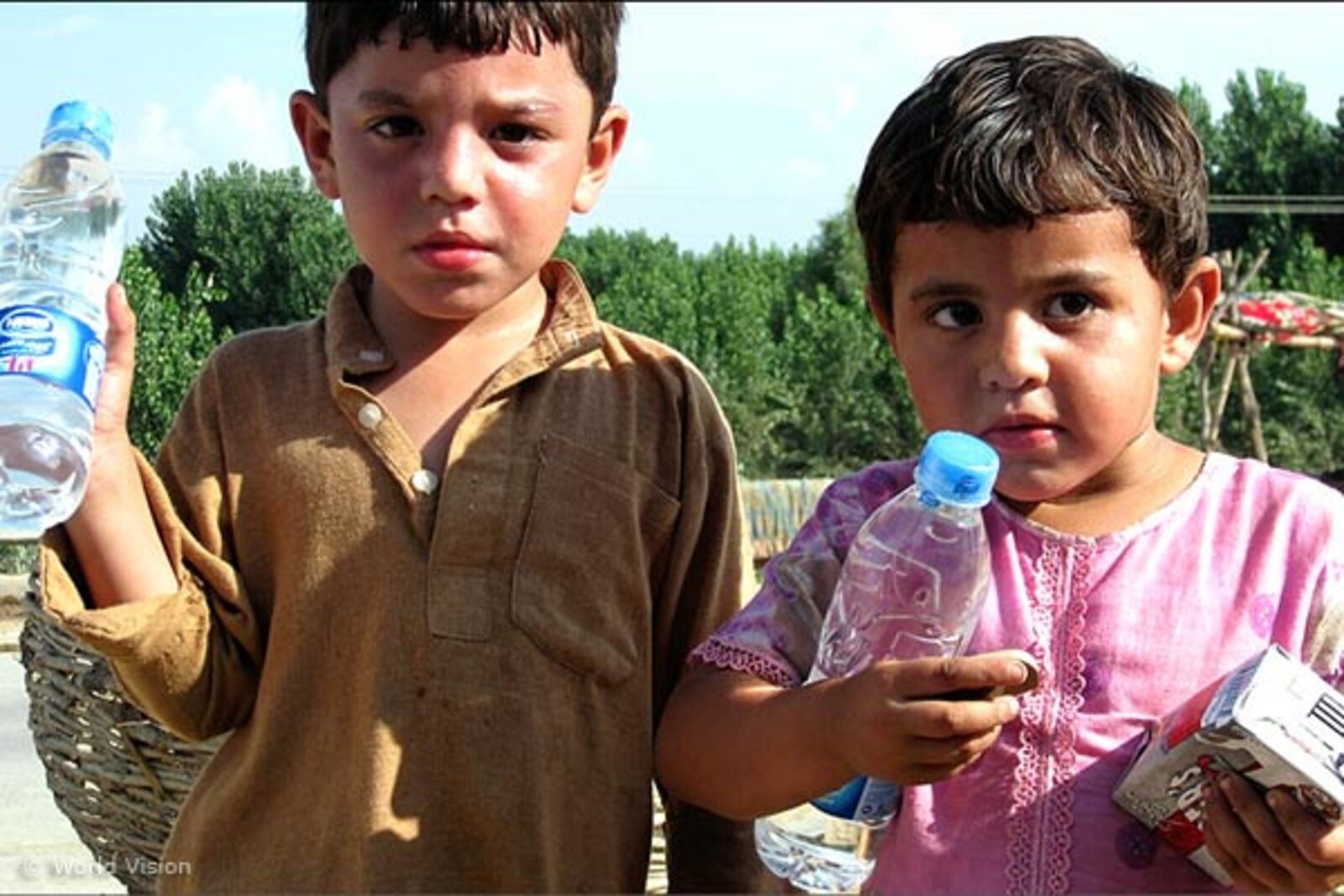 Flut Pakistan: Portrait von 2 Kindern mit Wasserflasche