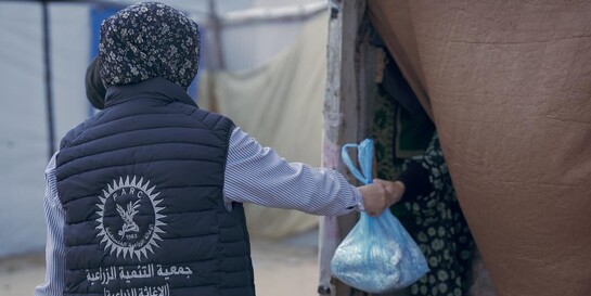 Eine Helferin reicht im Gazastreifen eine Tüte mit Essen in eine Notunterkunft