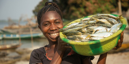 Eine Frau in Sierra Leone hält eine Schüssel mit Fischen in den Händen