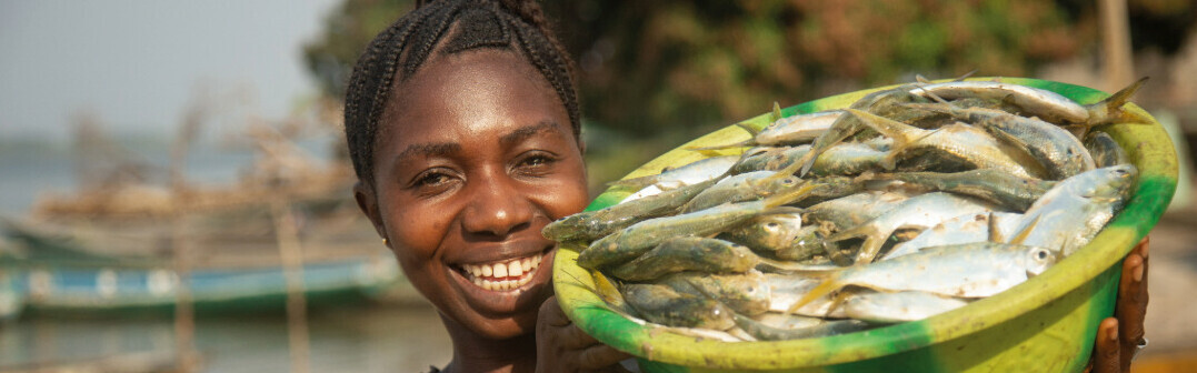 Eine Frau in Sierra Leone hält eine Schüssel mit Fischen in den Händen