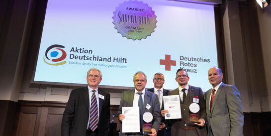 Bernd Pastors, Vorstandsvorsitzender von Aktion Deutschland Hilft (2.v.l.), nimmt den Superbrands Preis entgegen