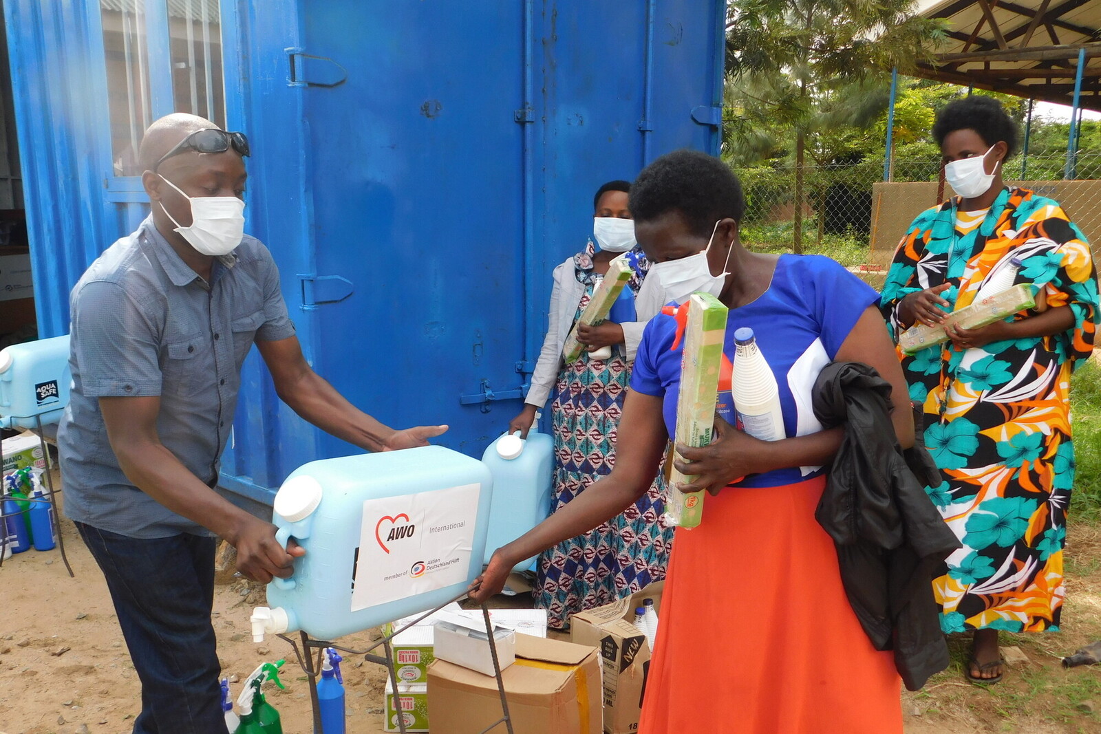 Ein Helfer gibt einer Frau in Uganda einen Kanister mit Trinkwasser