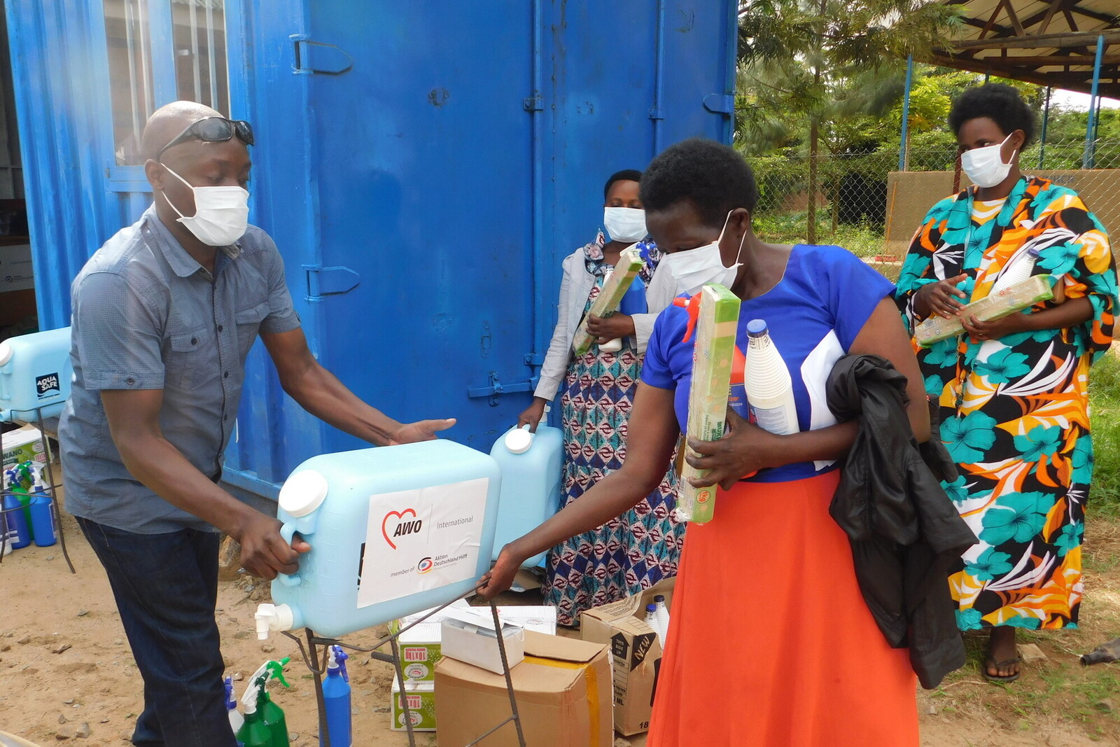 Ein Helfer gibt einer Frau in Uganda einen Kanister mit Trinkwasser