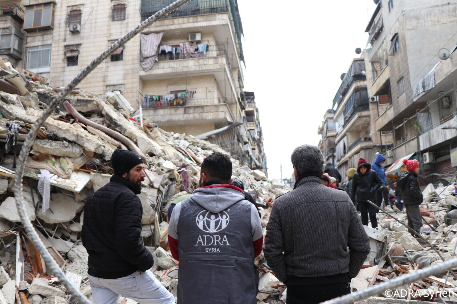 Helfer von ADRA vor vom Erdbeben zerstörten Häuser in Syrien 