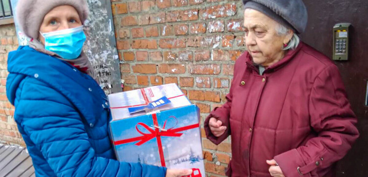 Ältere Frau aus der Ukraine erhält ein Hilfspaket der Malteser