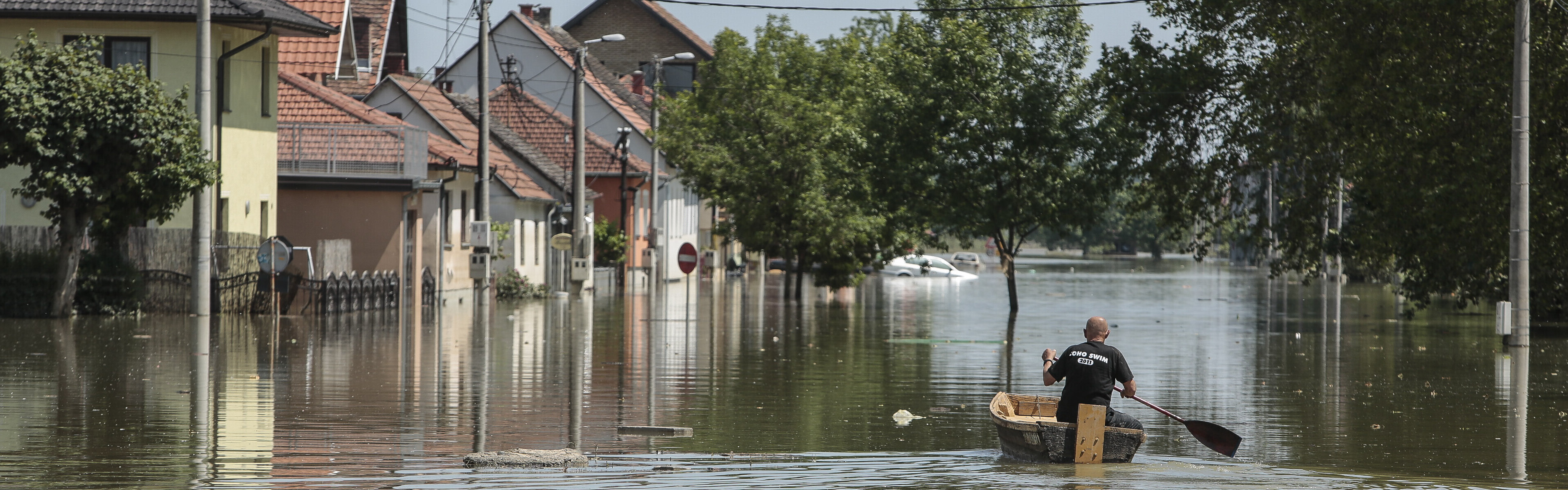 Mann im Boot auf überschwemmter Straße