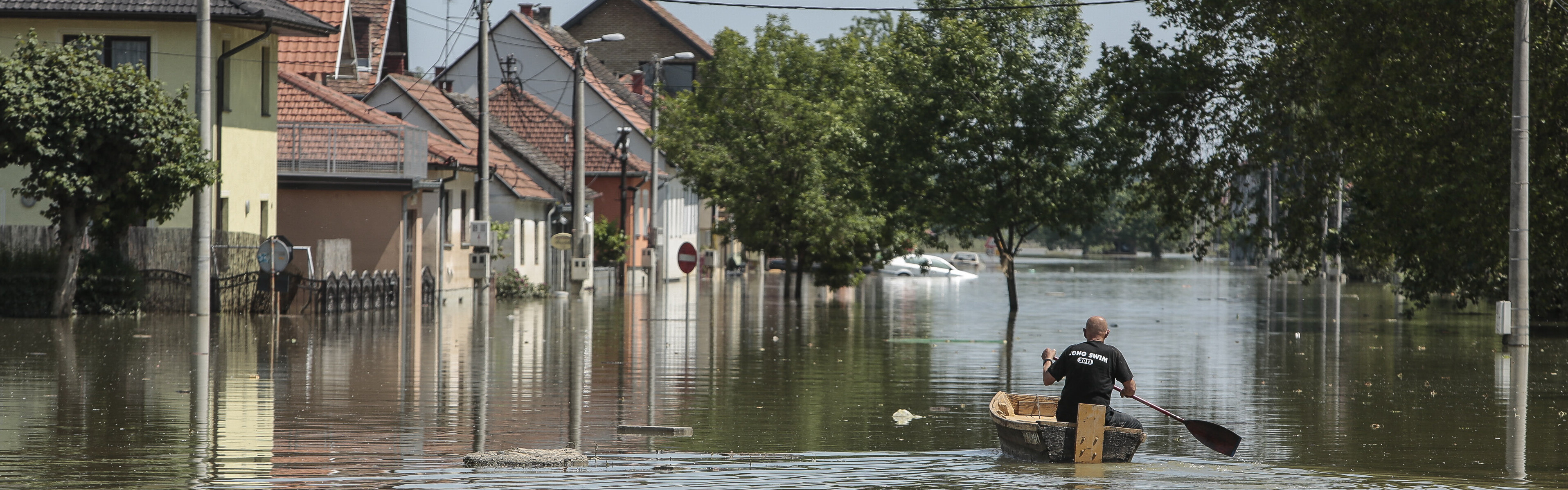 Mann im Boot auf überschwemmter Straße