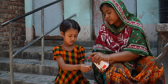 Einem Kind in Bangladesch werden die Hände desinfiziert