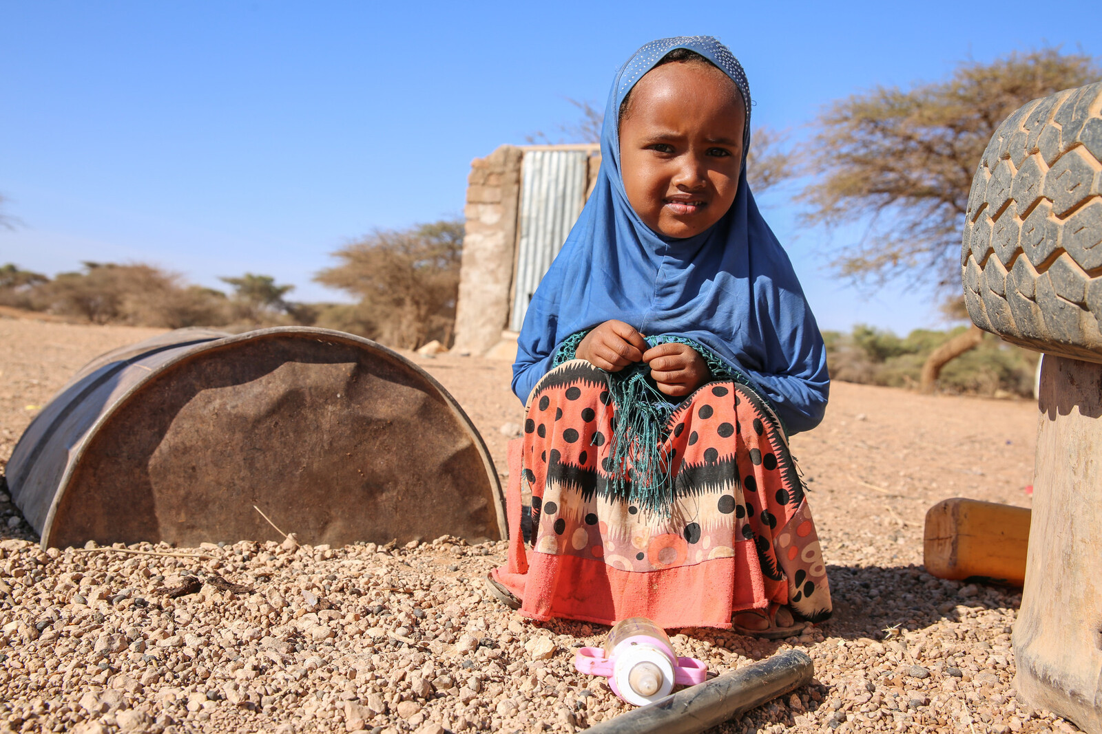 Ein kleines Mädchen auf einem Spielplatz in Somalia hockt auf einem ausgetrockneten Boden