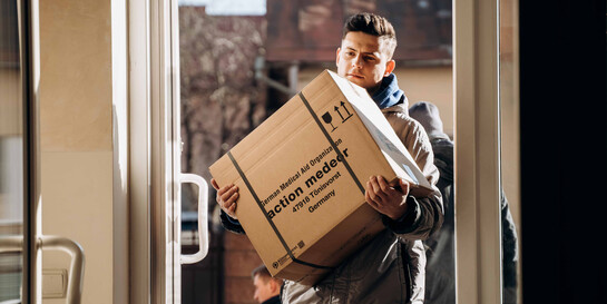 Ein Helfer trägt ein Paket mit medizinischen Hilfsgütern