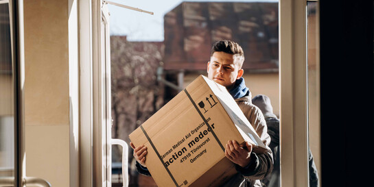 Ein Helfer trägt ein Paket mit medizinischen Hilfsgütern