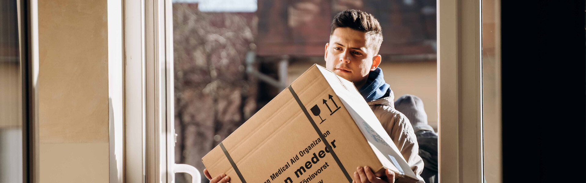Ein Helfer trägt ein Paket mit medizinischen Hilfsgütern