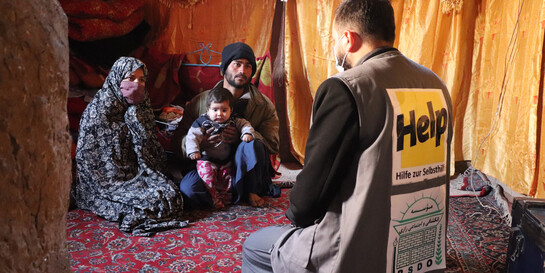 Eine afghanische Familie spricht mit einem Helfer der Organisation Help – Hilfe zur Selbsthilfe