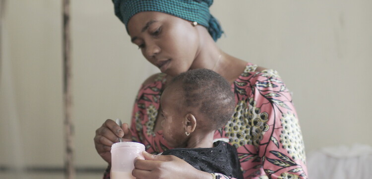 Eine Frau gibt einem Kind in der DR Kongo Nahrung