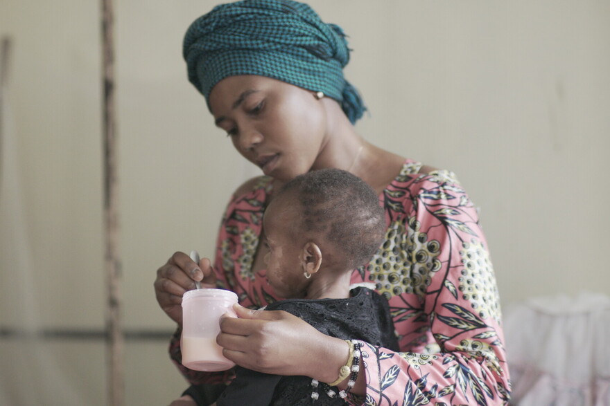 Eine Frau gibt einem Kind in der DR Kongo Nahrung