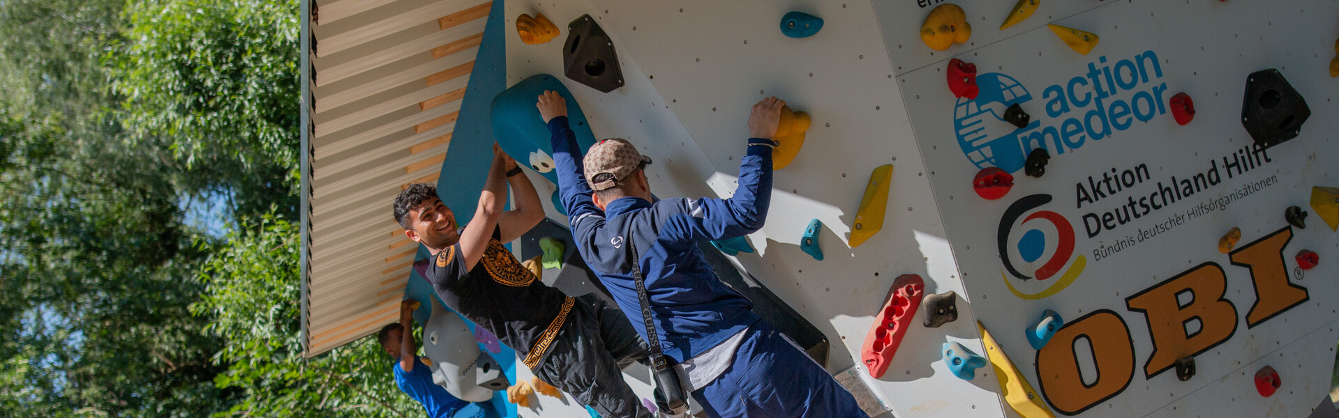 Kinder und Erwachsene klettern an einem Boulder-Würfel