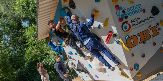 Kinder und Erwachsene klettern an einem Boulder-Würfel