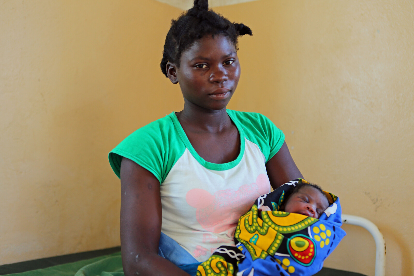 Eine junge Frau in Mosambik hält ihre Tochter auf dem Arm