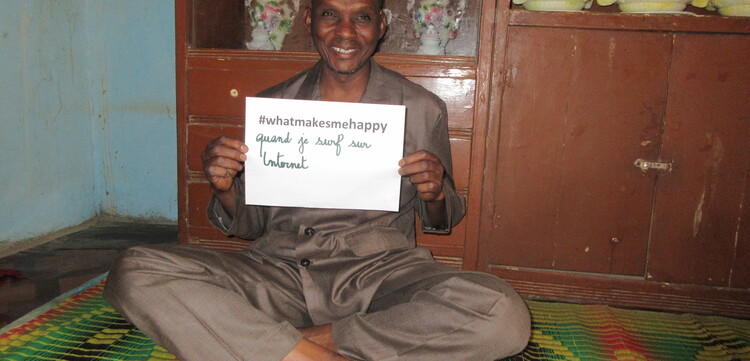 Ein Mann, Bounou Mamane, hält ein Schild hoch mit der Aufschrift "#whatmakesmehappy"