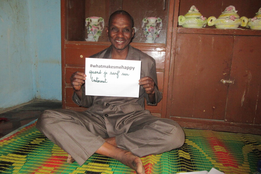 Ein Mann, Bounou Mamane, hält ein Schild hoch mit der Aufschrift "#whatmakesmehappy"