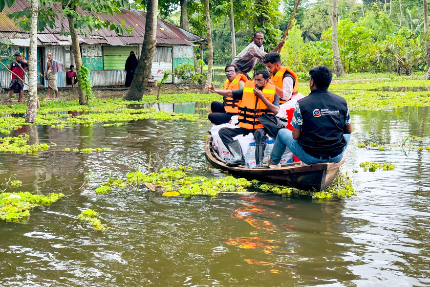 Männer in einem Boot liefern Lebensmittel und Wasser an überschwemmte Haushalte in Bangladesch Männer in einem Boot liefern Lebensmittel und Wasser an überschwemmte Haushalte in Bangladesch