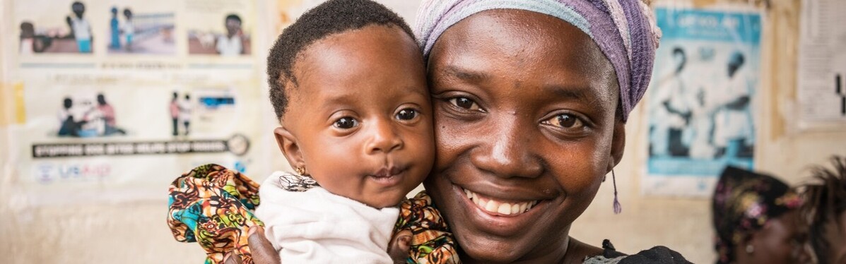 In Sierra Leone hält eine Frau in einer Hebammenschule ein Kind im Arm In Sierra Leone hält eine Frau in einer Hebammenschule ein Kind im Arm
