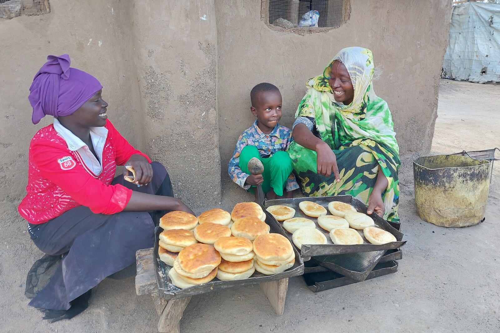 Zwei Frauen und ein Junge backen Brot im Geflüchtetencamp