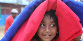 Ein Rohingya-Mädchen versteckt sich unter wärmenden Decken in einem Flüchtlingscamp in Bangladesch