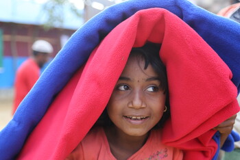 Ein Rohingya-Mädchen versteckt sich unter wärmenden Decken in einem Flüchtlingscamp in Bangladesch