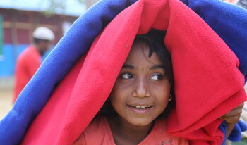 Ein Rohingya-Mädchen versteckt sich unter wärmenden Decken in einem Flüchtlingscamp in Bangladesch