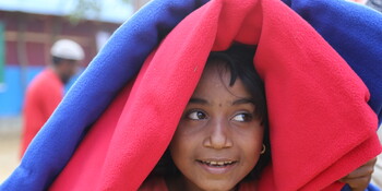 Ein Rohingya-Mädchen versteckt sich unter wärmenden Decken in einem Flüchtlingscamp in Bangladesch