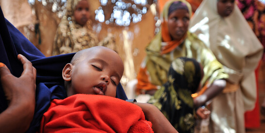 Ein kleines Kind schläft auf dem Arm seiner Mutter in einem Flüchtlingszelt an der Grenze zu Somalia. Vor Kriegen und Gewalt fliehen dort immer mehr Menschen.