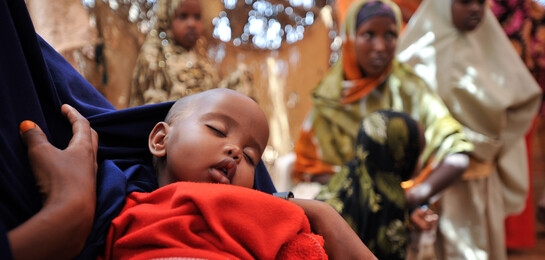 Ein kleines Kind schläft auf dem Arm seiner Mutter in einem Flüchtlingszelt an der Grenze zu Somalia. Vor Kriegen und Gewalt fliehen dort immer mehr Menschen.