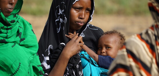 Eine Frau in Somalia mit ihrem Kind auf dem Arm.