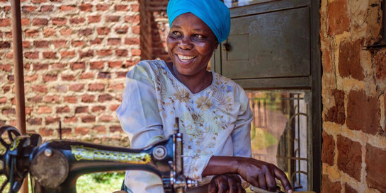 Eine Frau in Uganda sitzt an einer Nähmaschine