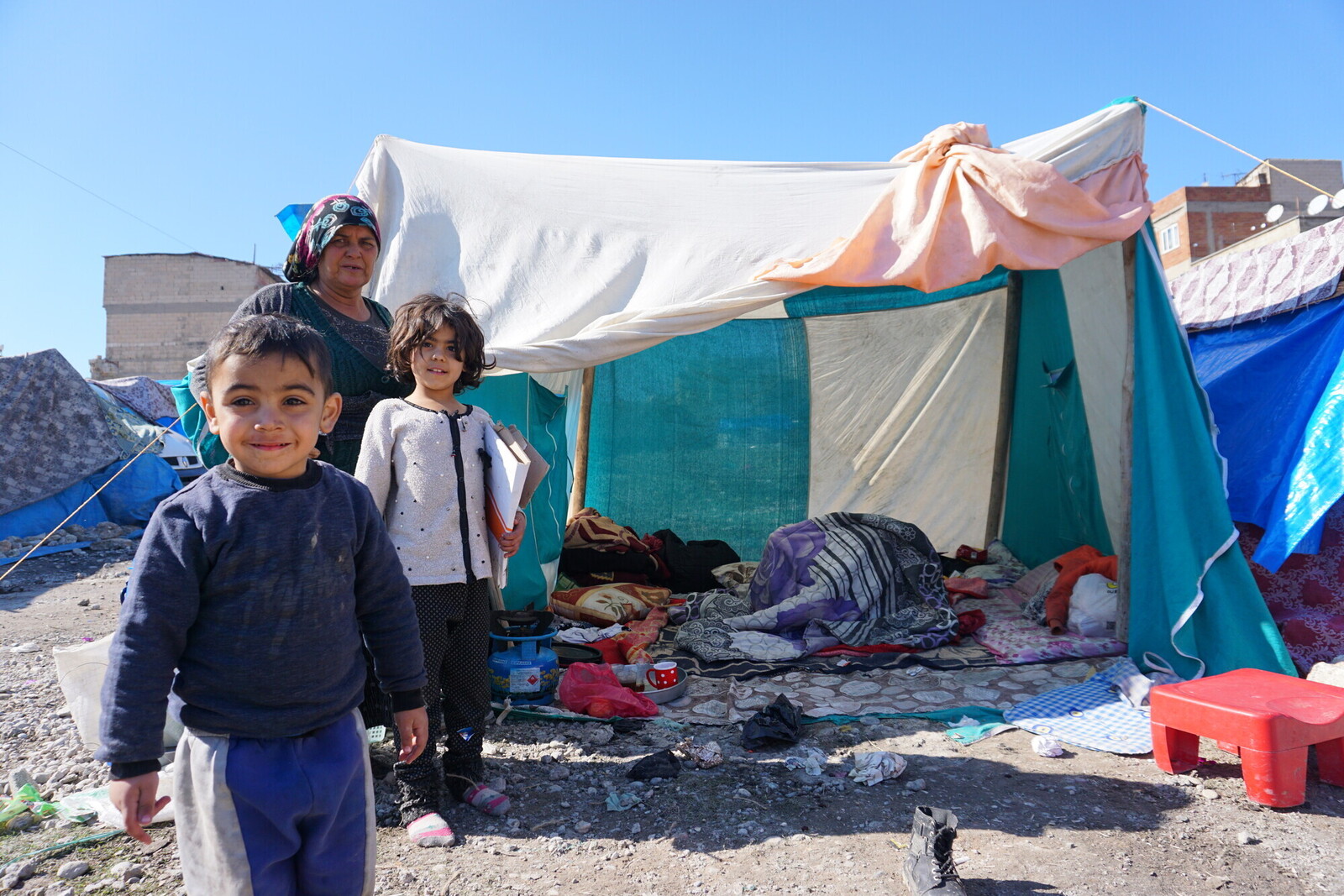 Drei Geflüchtete stehen vor einem Zelt in einem Camp in der Türkei