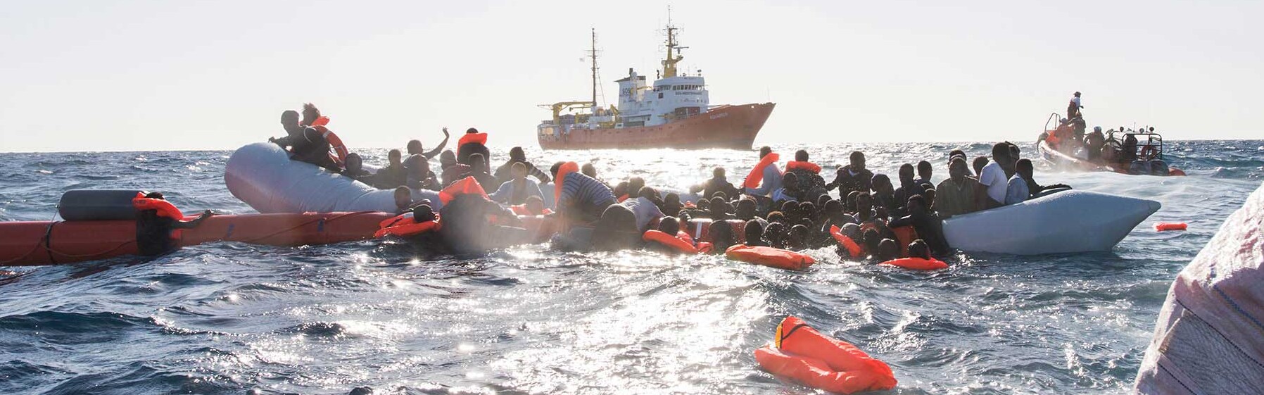 Menschen sind auf einem Schlauchboot im Mittelmeer und werden aus ihrer Seenot gerettet