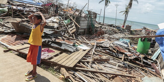 Ein Junge steht vor zerstörten Häusern nach einem schweren Taifun auf den Philippinen