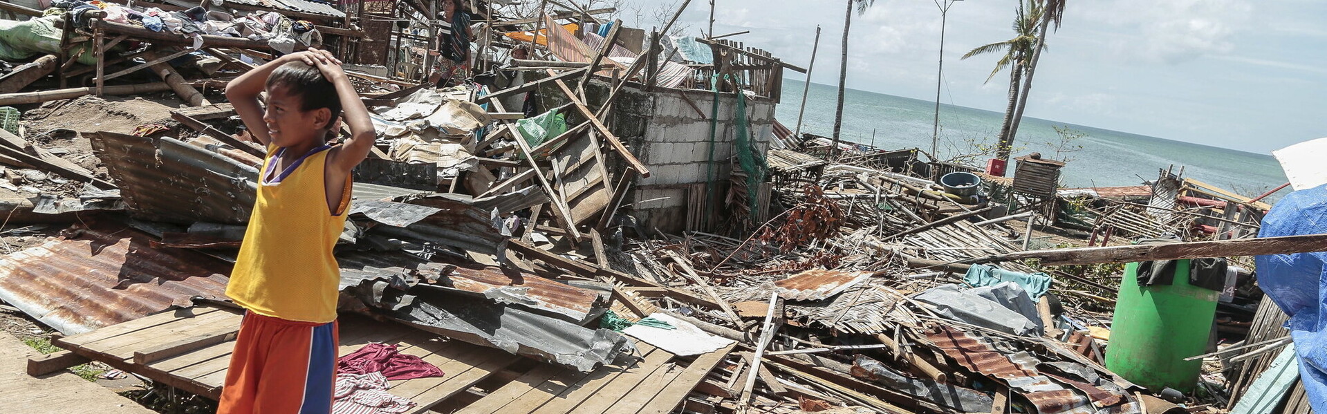 Ein Junge steht vor zerstörten Häusern nach einem schweren Taifun auf den Philippinen
